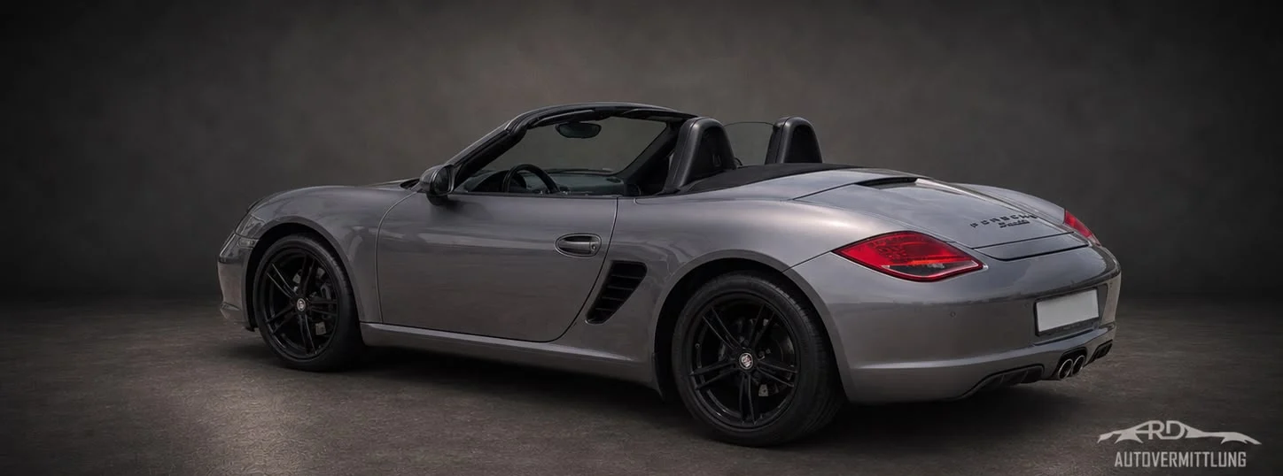 Grauer Porsche Boxster der Baureihe 987 mit offenem Verdeck, Heckansicht im Studio
